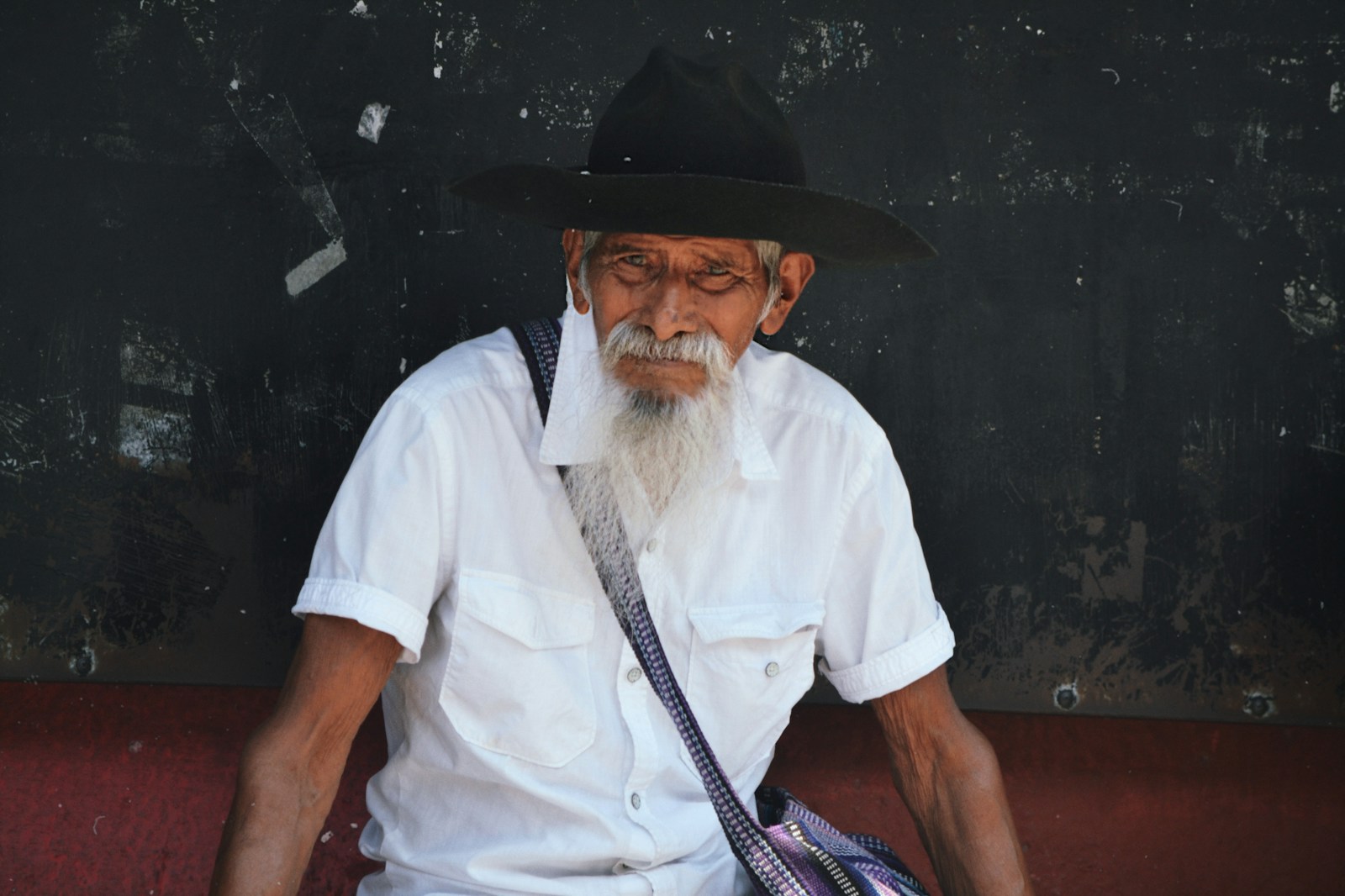 An old man sitting on a bench wearing a hat